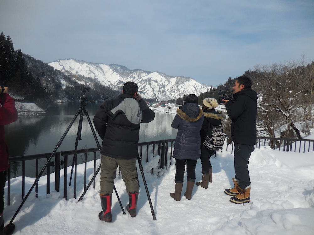 雪の中を三脚と望遠レンズの装備で撮影する